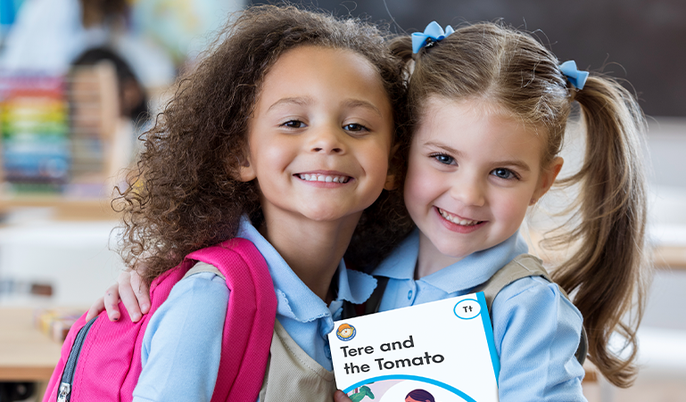 Two students holding up a letter book